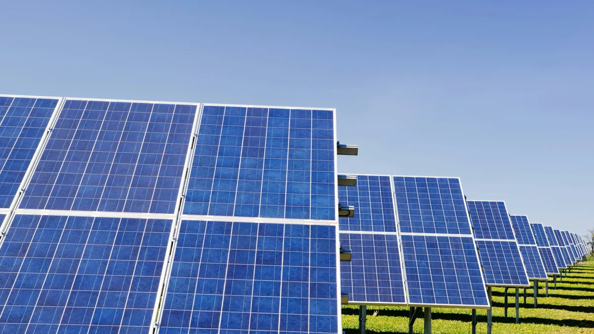 A field of solar panels arranged in rows, with each panel consisting of multiple blue photovoltaic cells.