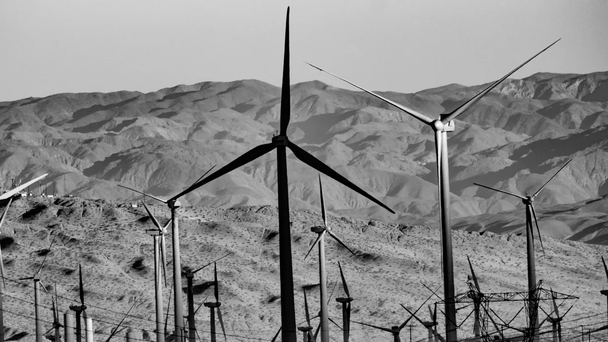 A wind farm with multiple wind turbines standing in a desert landscape.
