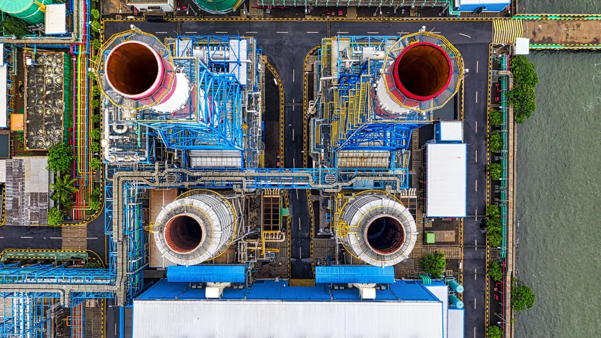 A power plant with multiple large pipes and structures, situated near a body of water.