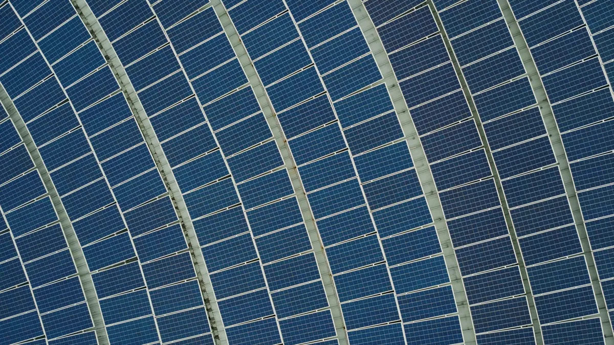 A large array of solar panels arranged in rows, with each panel consisting of multiple smaller photovoltaic cells.