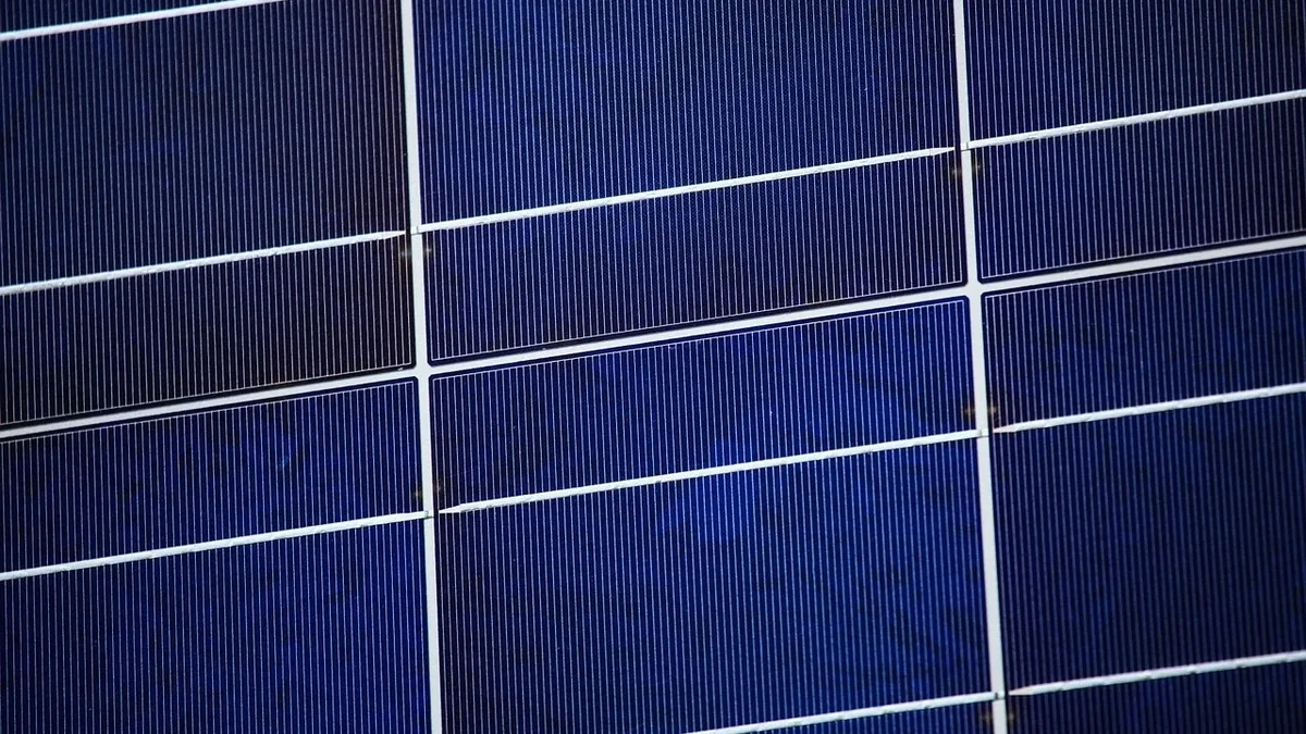A close-up view of a solar panel, comprising multiple dark blue rectangular cells with white lines separating them.