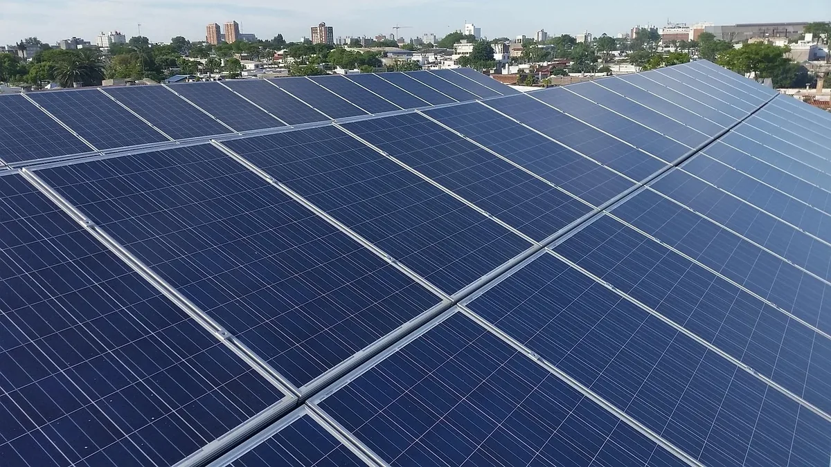 A large array of solar panels installed on a rooftop, with a cityscape visible in the background.