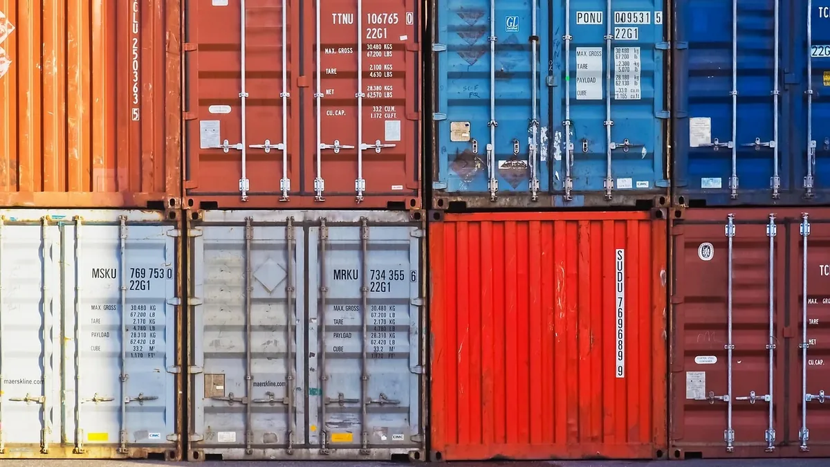 A stack of shipping containers, with some containers open and others closed, in a warehouse or storage yard setting.