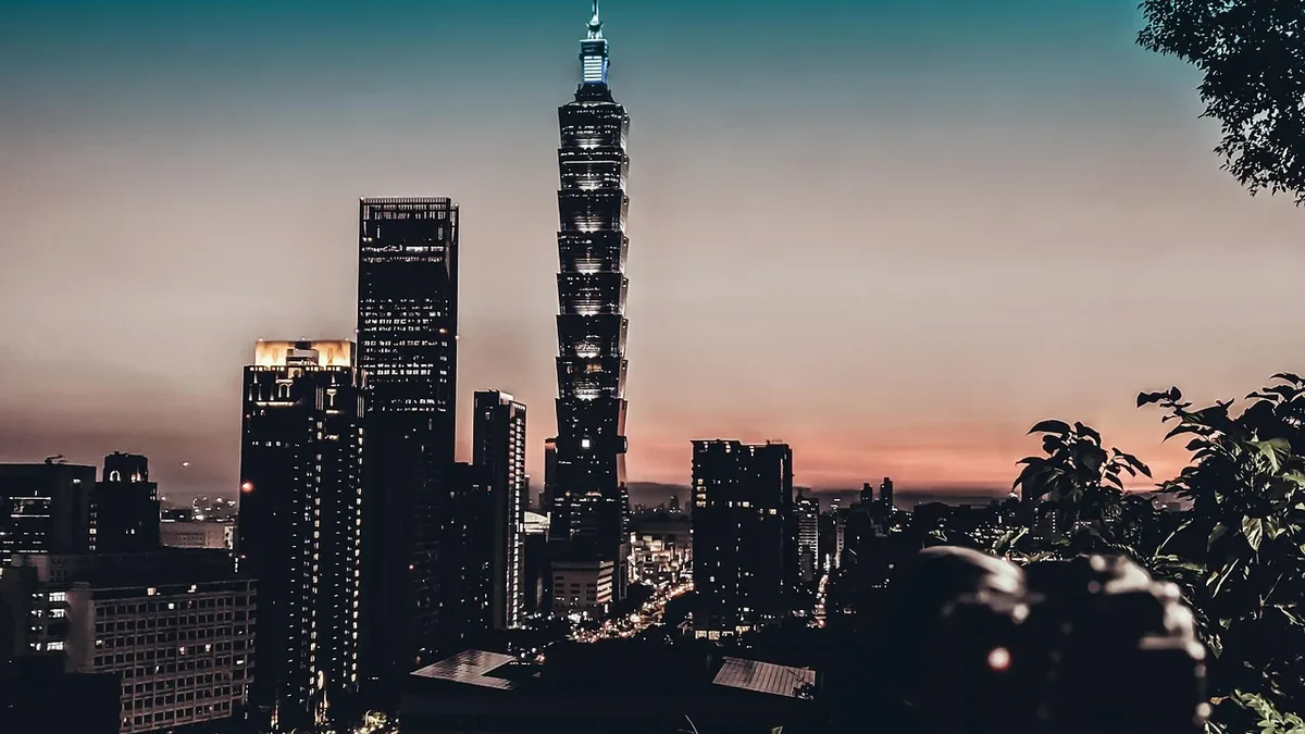 The Taipei 101 skyscraper, a prominent building in Taipei, Taiwan, set against a backdrop of other buildings and trees.