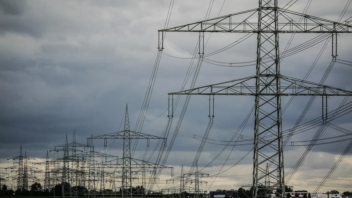 A field with multiple power transmission towers, each featuring a tall metal structure with multiple wires and cables attached.