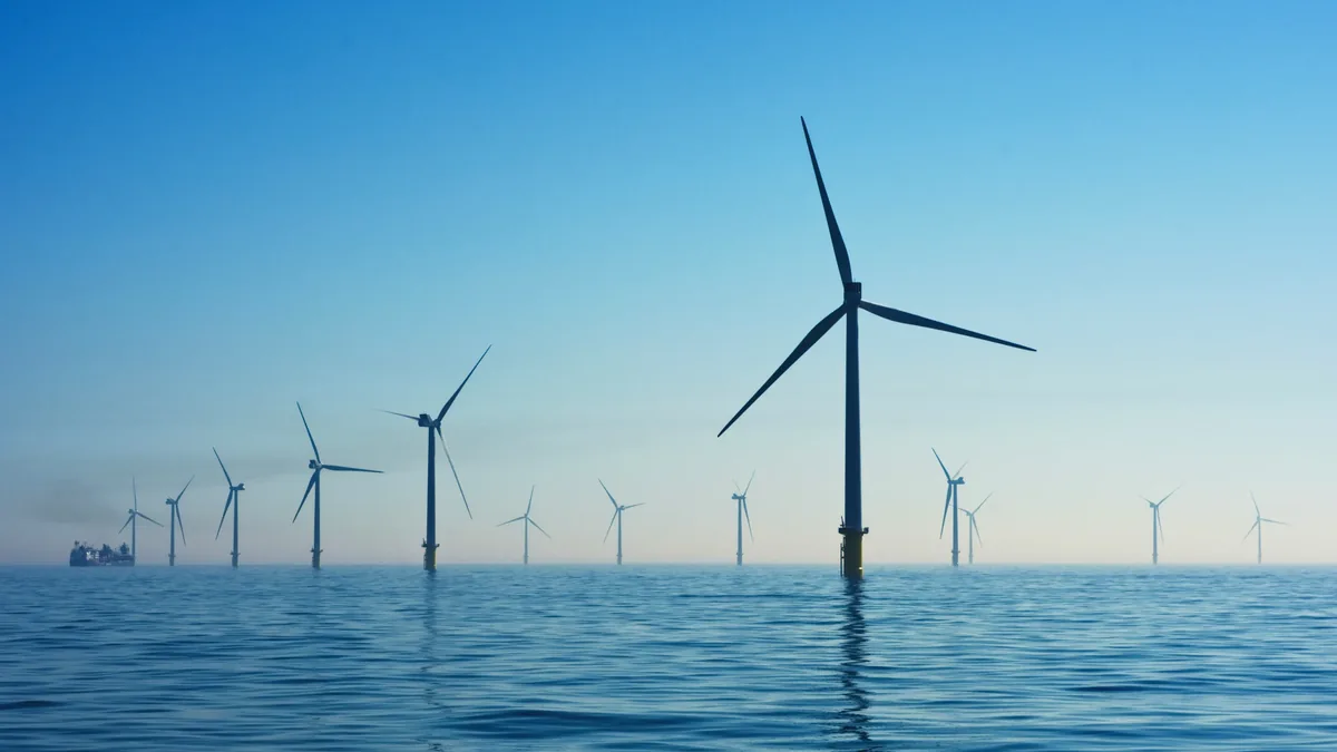 A large body of water with multiple wind turbines standing in it, their blades visible and angled to catch the wind.